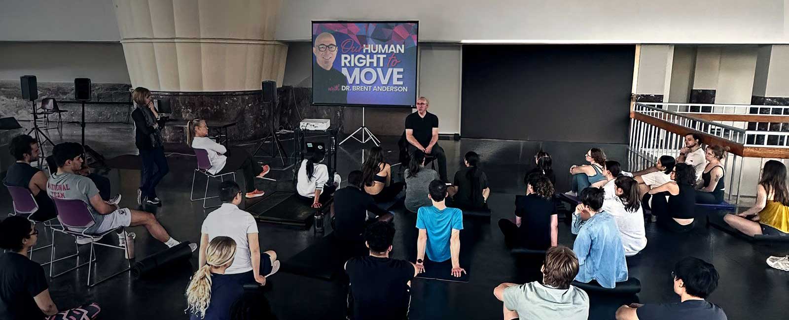Dr. Brent Anderson teaching in a large room with a group of listeners